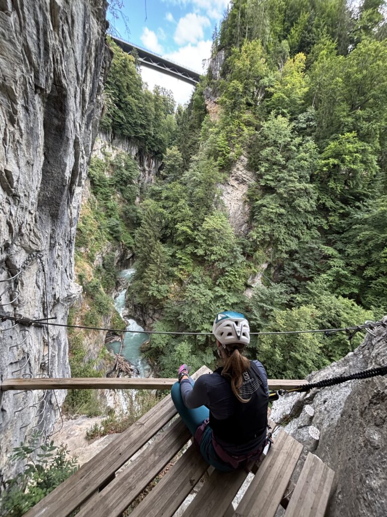 Moteris sėdi ant platformos via ferratos maršrute