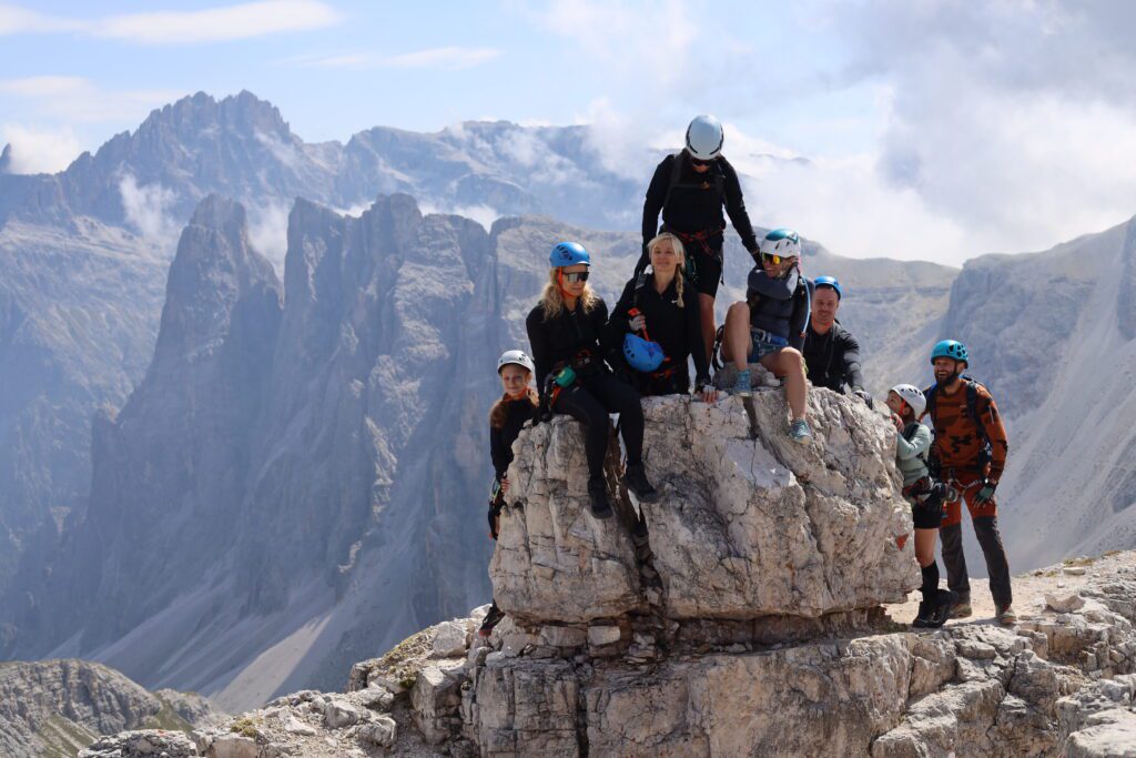 Žmonių kompanija sėdinti ant akmens Torre di Tobin kalno viršūnėje