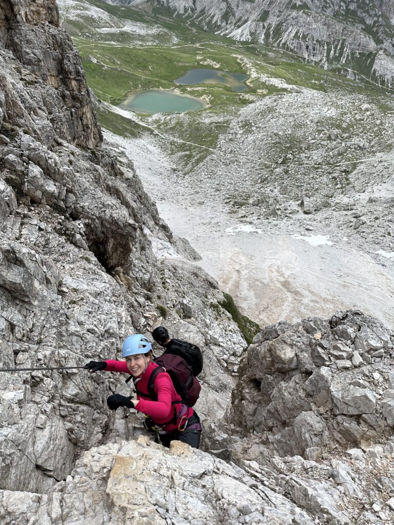 Via Ferrata de Luca – Innerkofler maršrutu lipanti moteris ir vyras su kalnais ir ežerėliais fone.