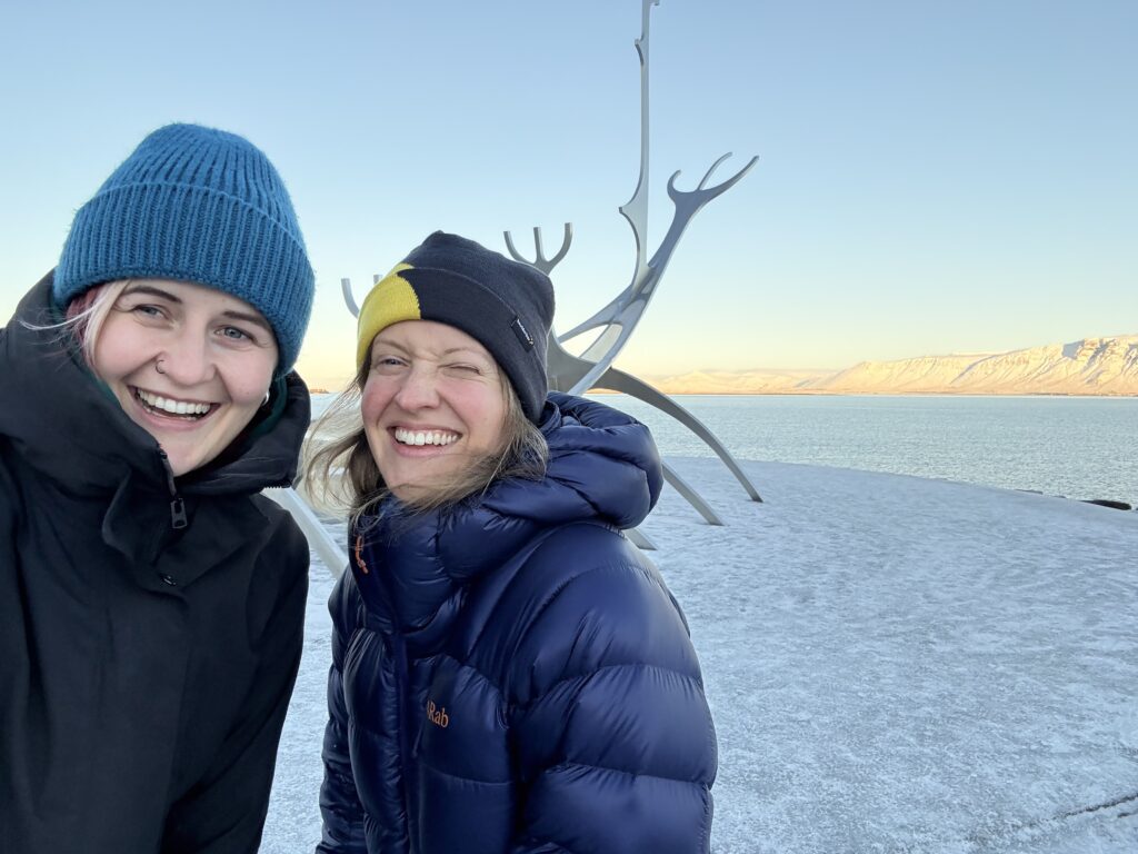 Kelionė į Islandiją žiemą. Dvi moterys prie vikingų valties skulptūros Reikjavike